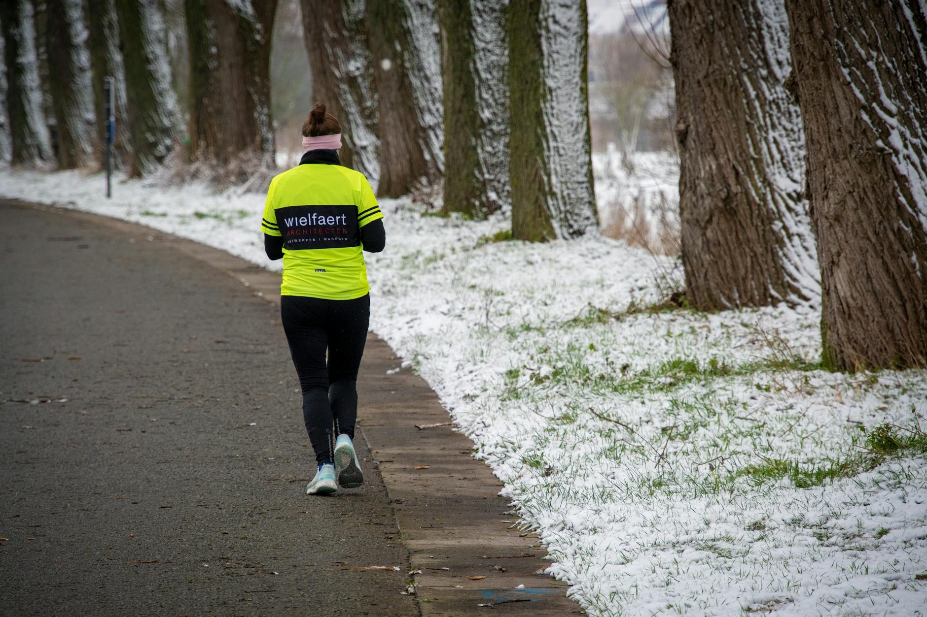 Kobieta po czterdziestce idzie zimą w stroju do biegania po ośnieżonej ścieżce