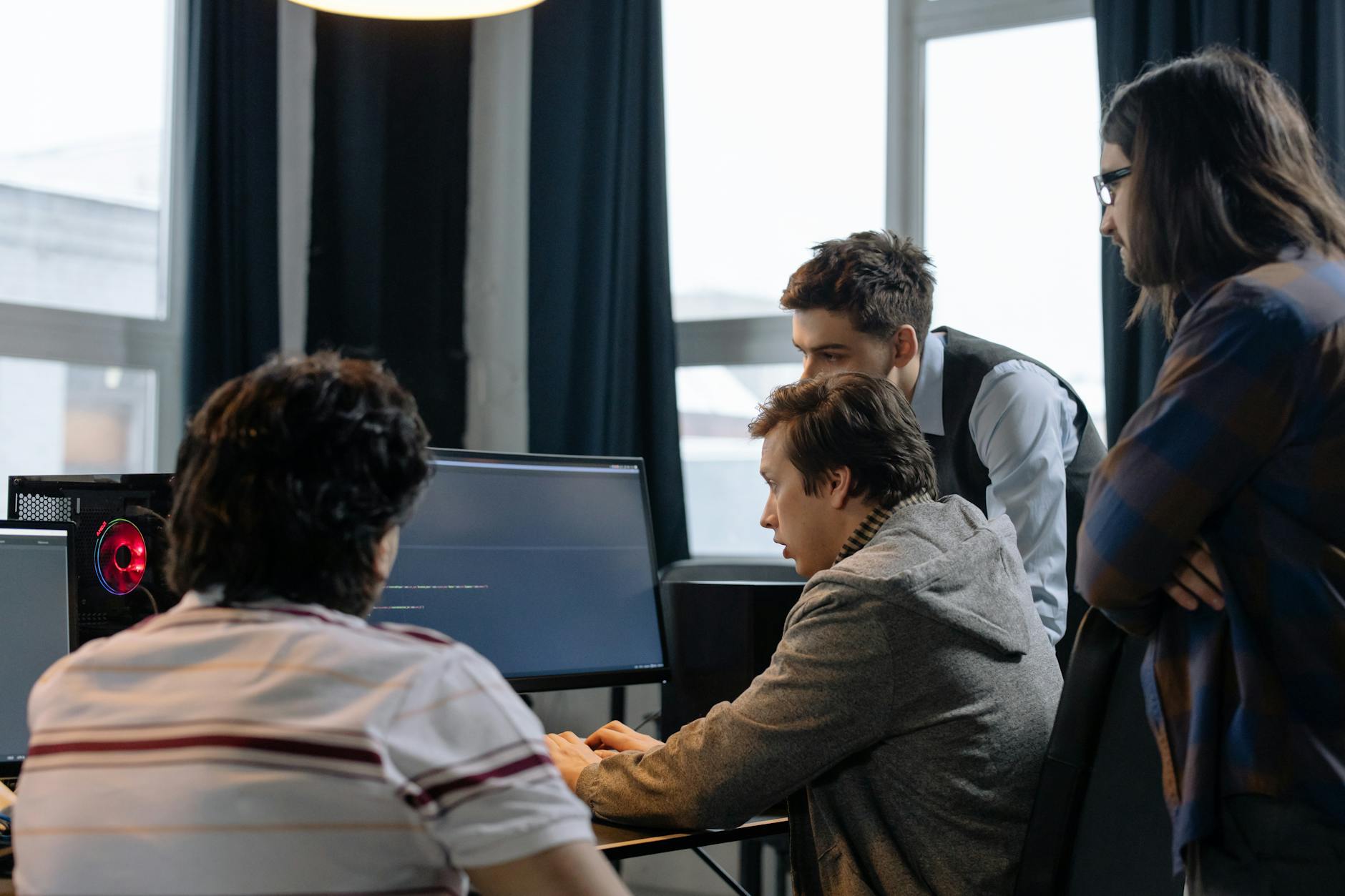 Zespół programistów pracuje wspólnie nad projektem przy komputerach