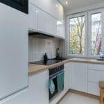 Jasna minimalistyczna kuchnia z białymi szafkami w mieszkaniu z rynku wtórnego