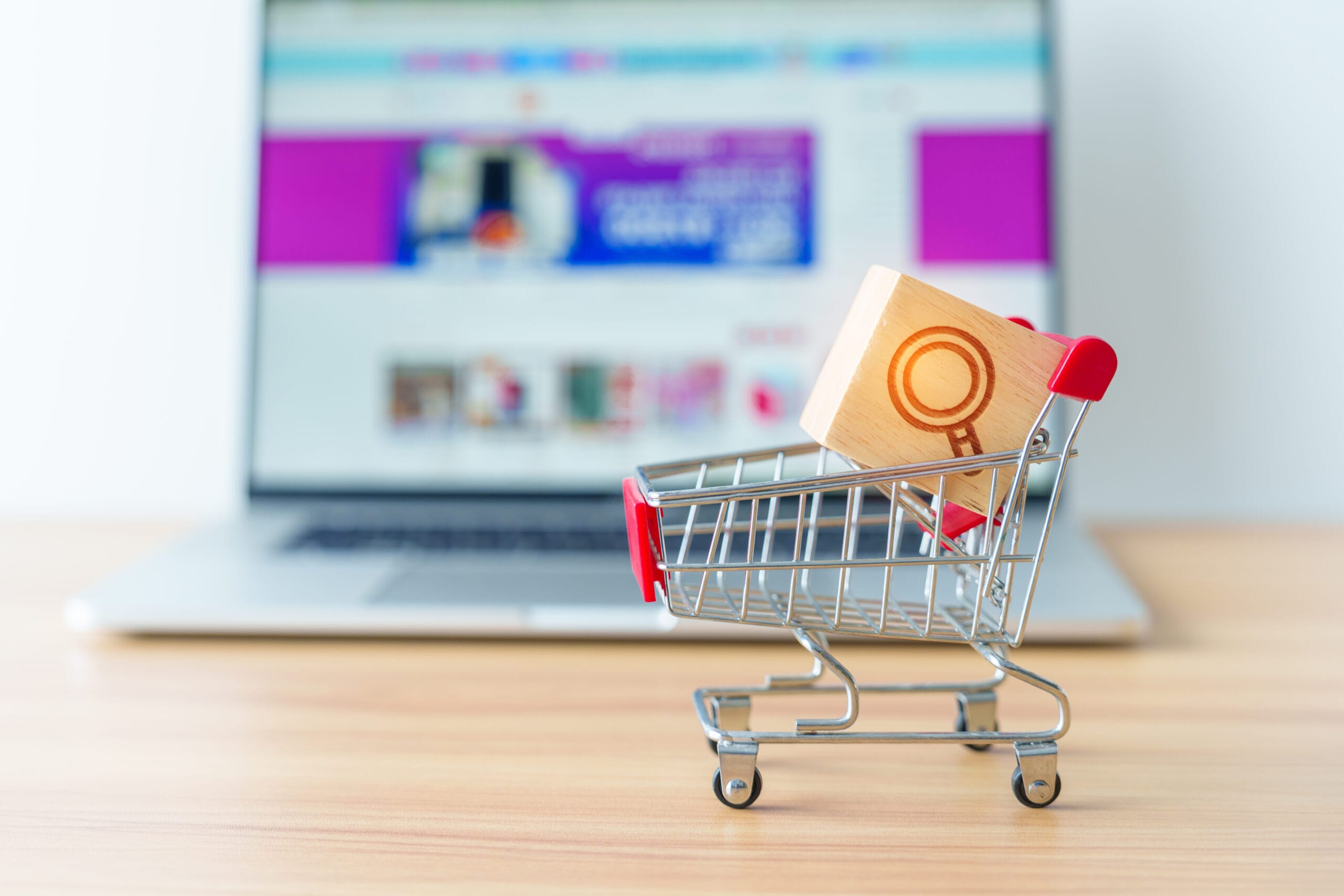 Shopping cart with Magnifying icon block and laptop computer wit
