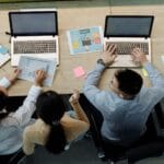 Zespół przy biurku tworzy dokumentację procesów na laptopach